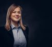 Close-up portrait of a smiling blonde businesswoman formal dressed. Isolated on a dark textured background.